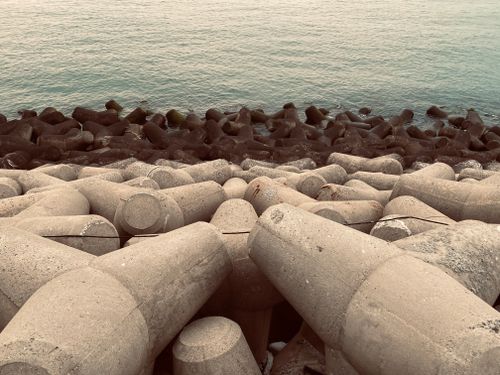 Free Shabby metal industrial structure covered with rust located on embankment of coastal city near rippling sea during daytime on street Stock Photo