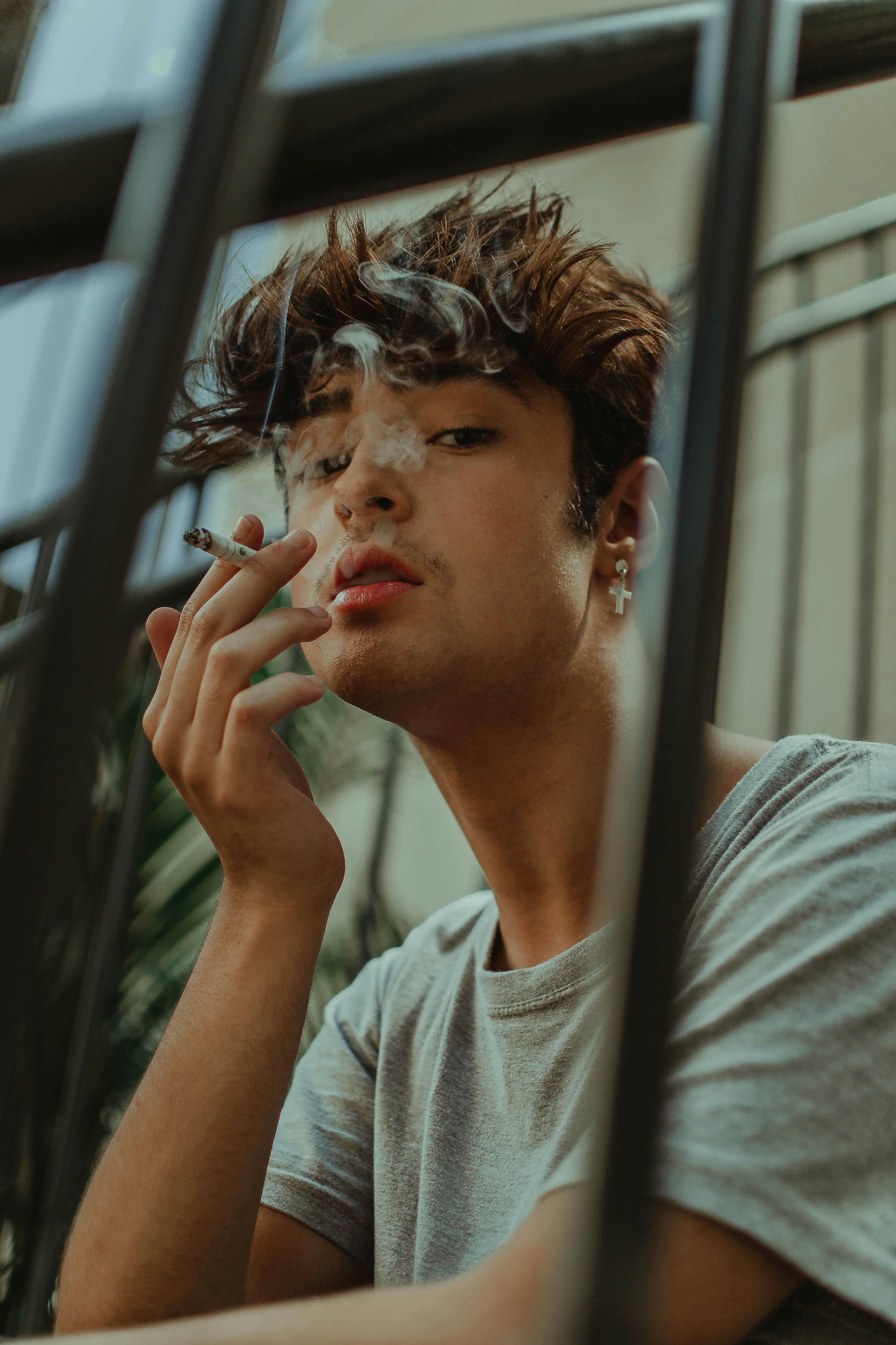 Young man smoking fence Free Stock Photo