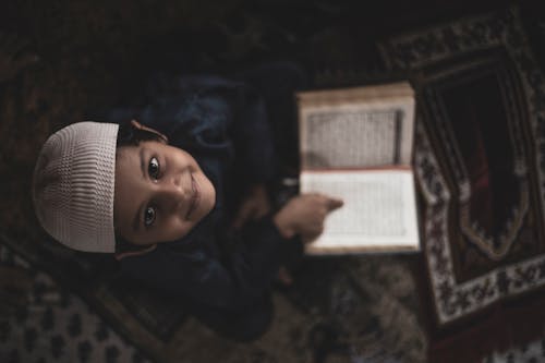 Boy in Head Covering Reading Quran