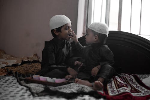 Little Boy Feeding His Brother with a Chocolate