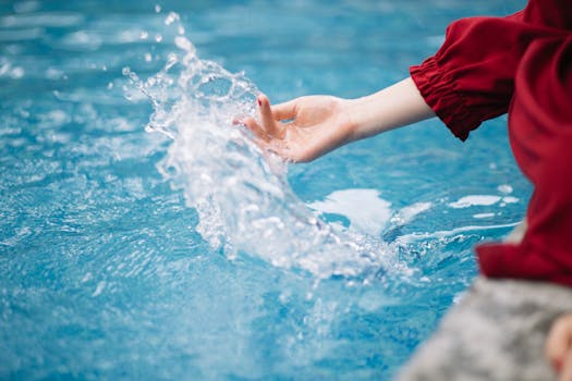 A close-up shot of a hand splashing water in a pool, capturing a refreshing summer moment.