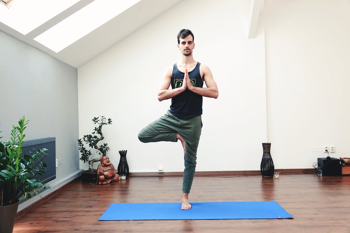 Young man doing yoga exercise on mat · Free Stock Photo