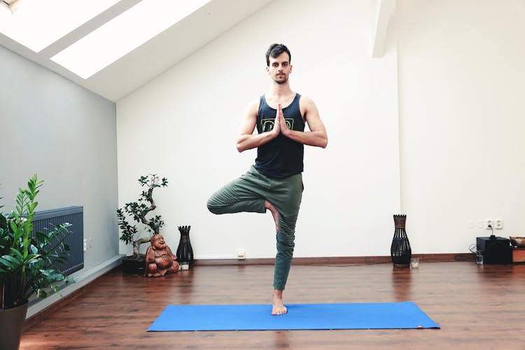 Young Man Doing Yoga Exercise On Mat