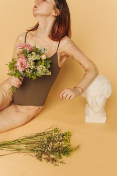 穿着泳衣的女人手捧花束，站在半身雕像旁，展现身体的活力