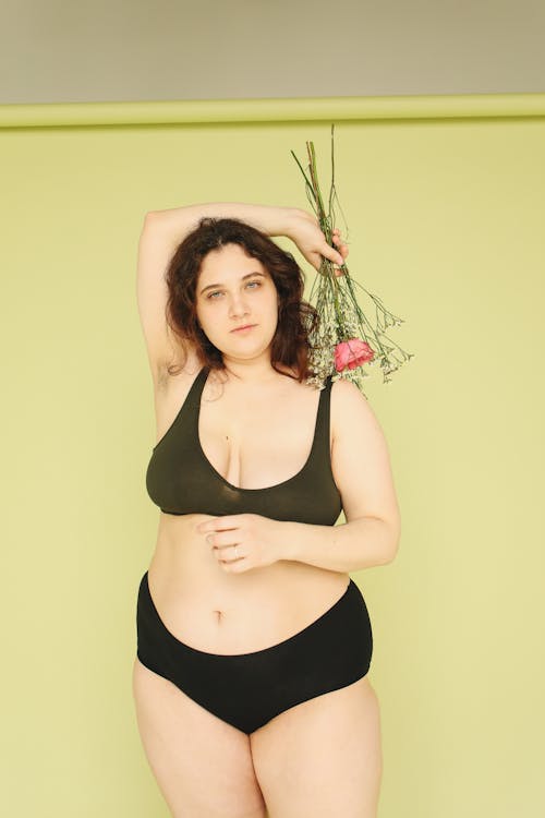 Woman in Black Lingerie Posing with a Bouquet of Flowers