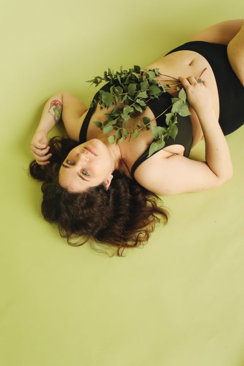 Free A beautiful woman in black underwear poses gracefully with leaves in a studio setting. Stock Photo