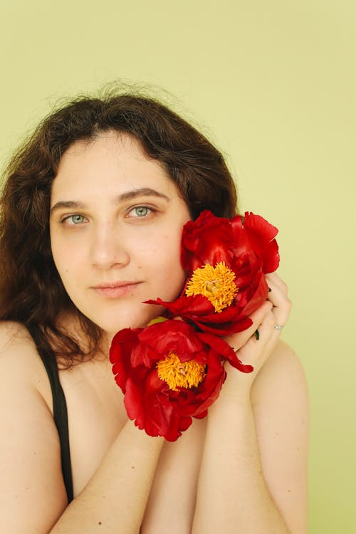 Woman Holding Red Flower Near her Face