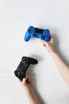 Two hands holding a blue and black gaming controller on a white background.