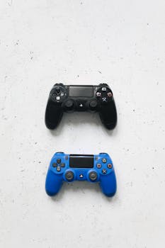 Top view of two gaming controllers, one black and one blue, on a white surface.