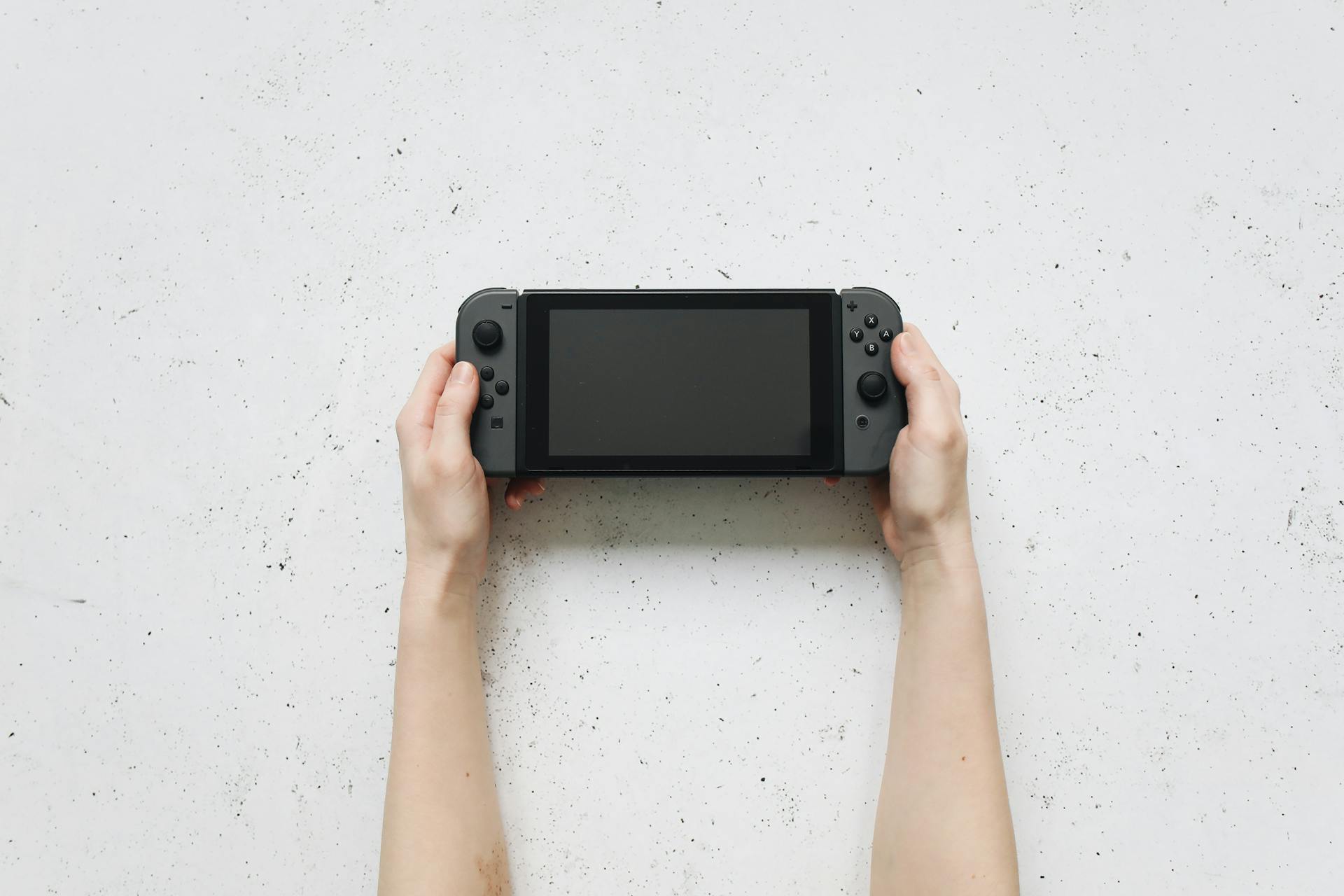 Hands Holding Nintendo Switch Near White Surface