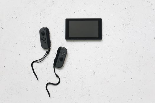Flat lay of a sleek gaming console with wireless controllers on a white background.