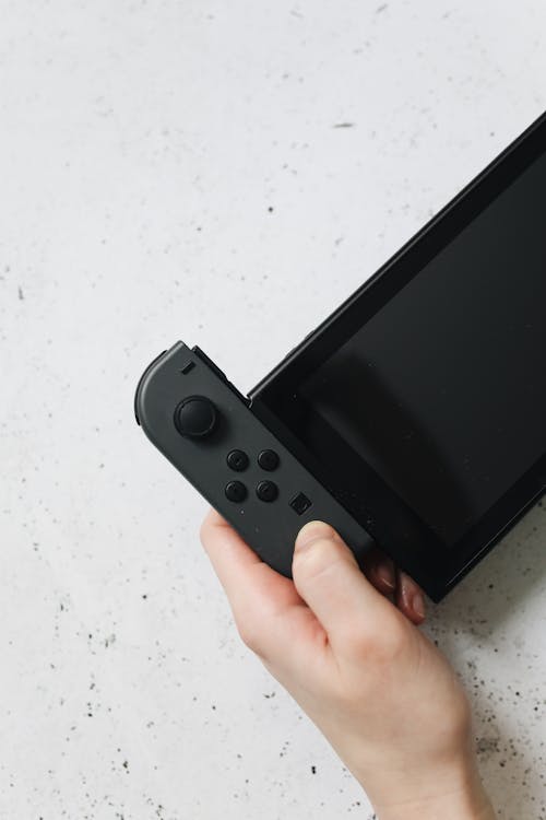 Person Holding Black Nintendo Switch in Close-up Photography