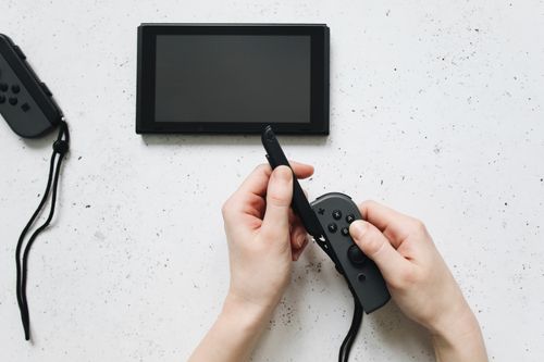 Free Close-up of hands holding a game controller on a white surface by a portable gaming device. Stock Photo