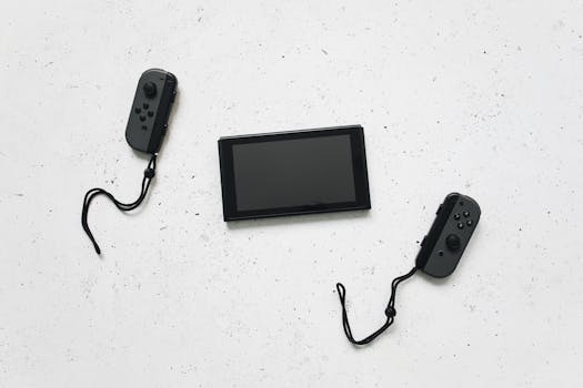 Flat lay of a Nintendo Switch and controllers on a white speckled surface, showcasing modern gaming tech.