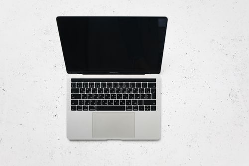 Free A sleek open laptop placed on a white marble surface, captured from above. Stock Photo