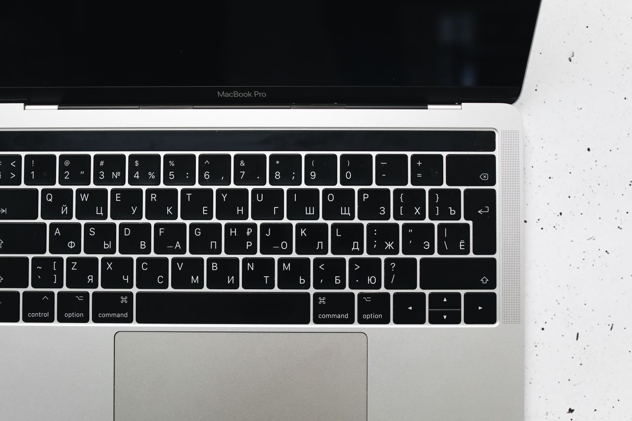 top view of a macbook pro keyboard on a speckled marble surface showca