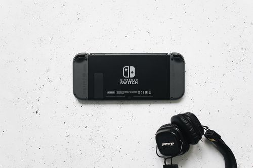 Free Nintendo Switch and headphones on a minimalist marble background, perfect for gaming content. Stock Photo