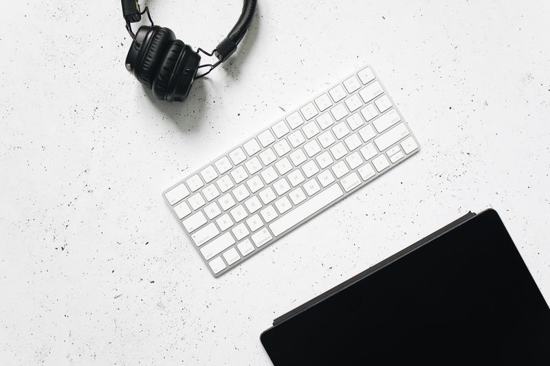 Black headphones beside a keyboard on a white desk