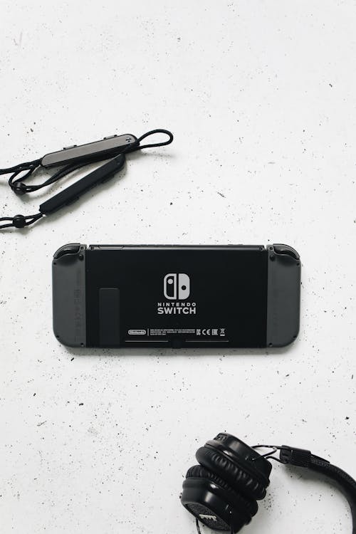 Nintendo Switch and a Black Headphones on a White Surface