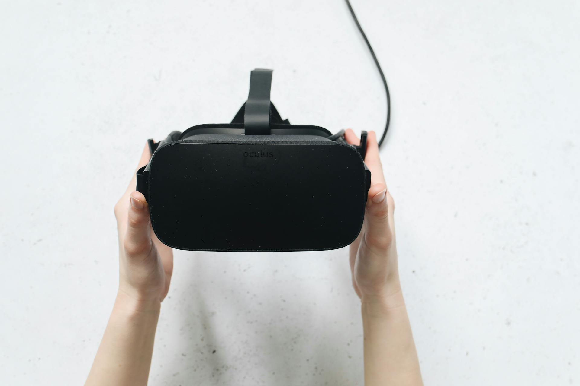 Close-up view of hands holding a VR headset, showcasing technology in a studio setting.