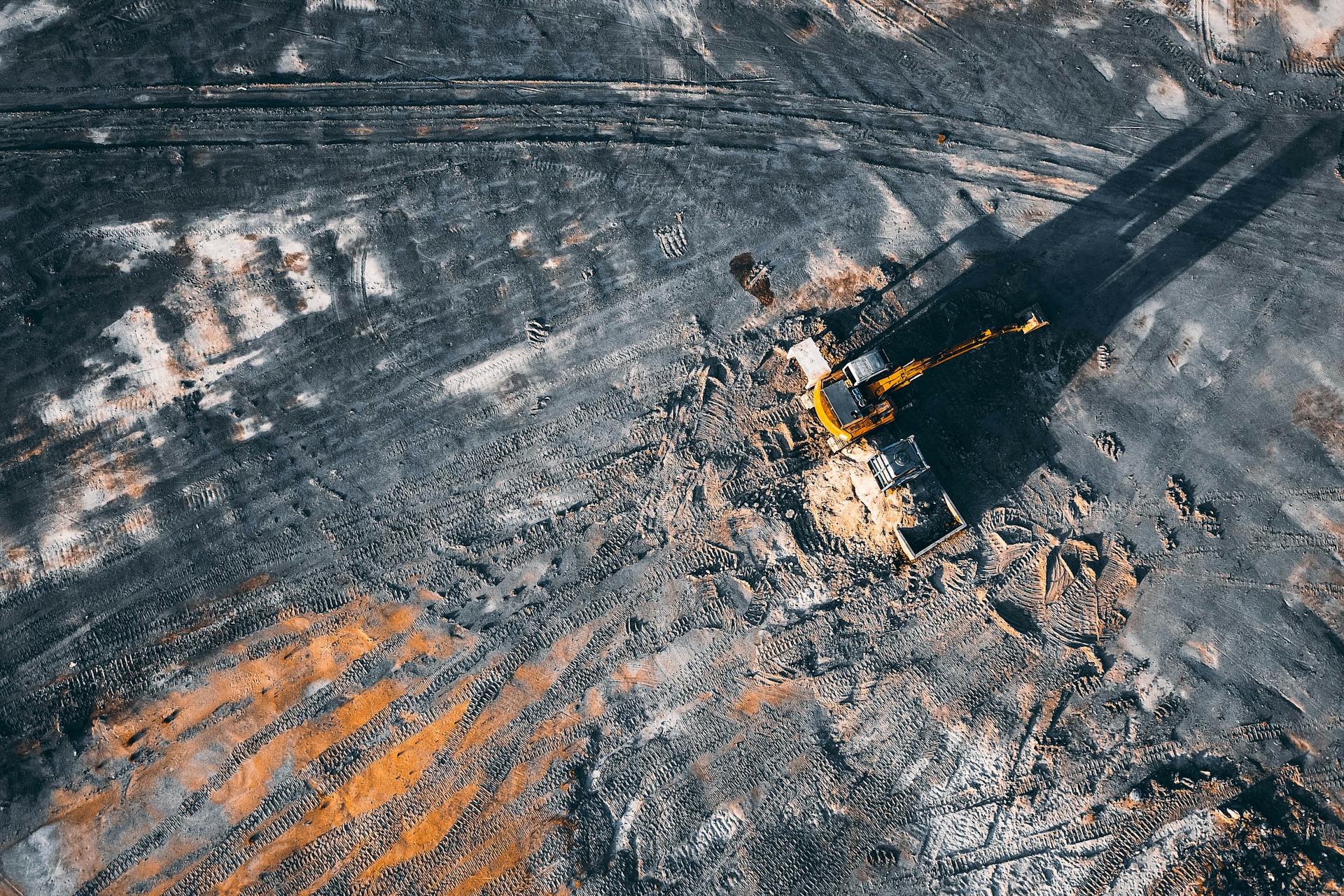 Aerial view of excavator working on big coal field of powerplant located in countryside