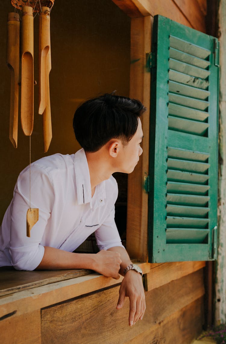 Contemplative Asian Man In Elegant Wear Looking Out Of Window