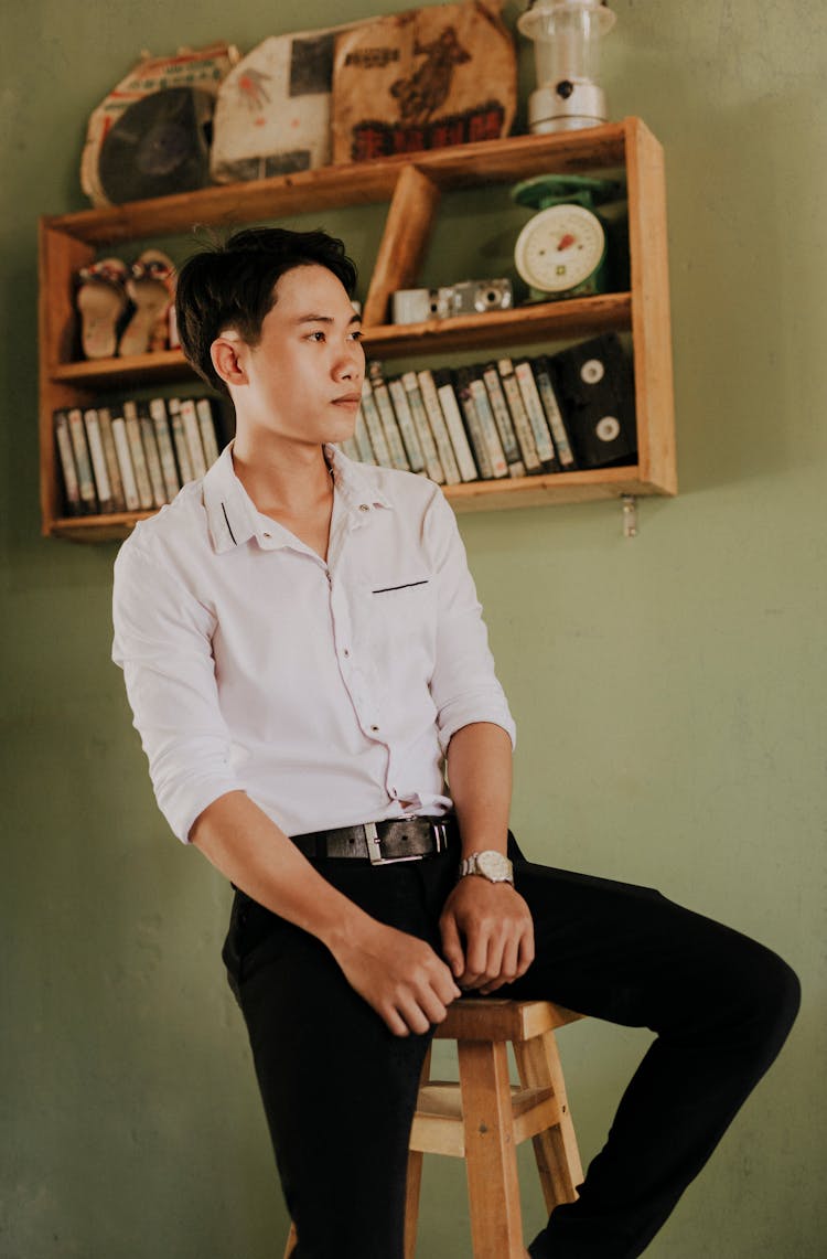 Wistful Asian Man In Trendy Clothes Resting On Stool