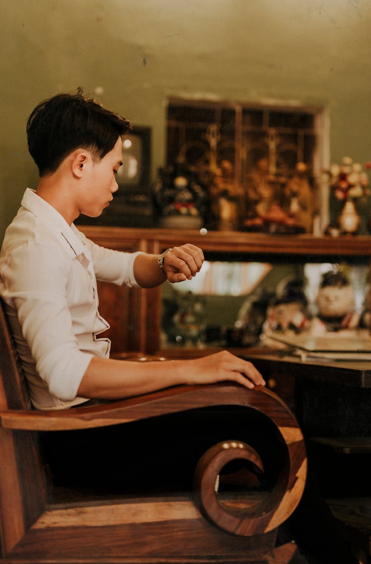 Elegant Asian Man Watching Time On Wristwatch At Home