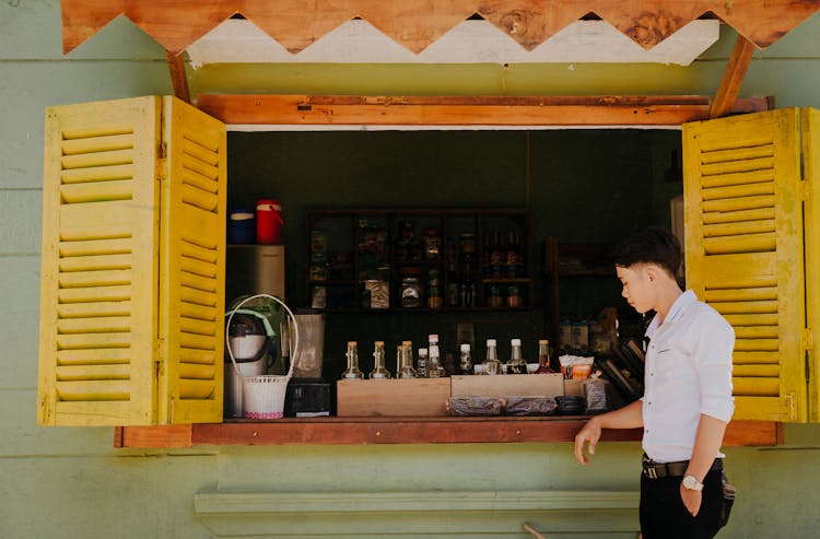 Stylish Asian Man Near Local Shop With Beverages For Sale