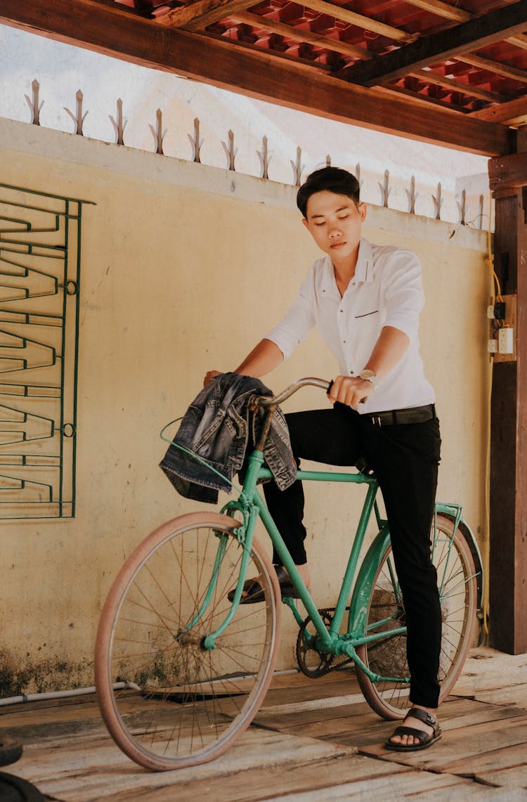 Melancholic Asian Man On Old Bike In House