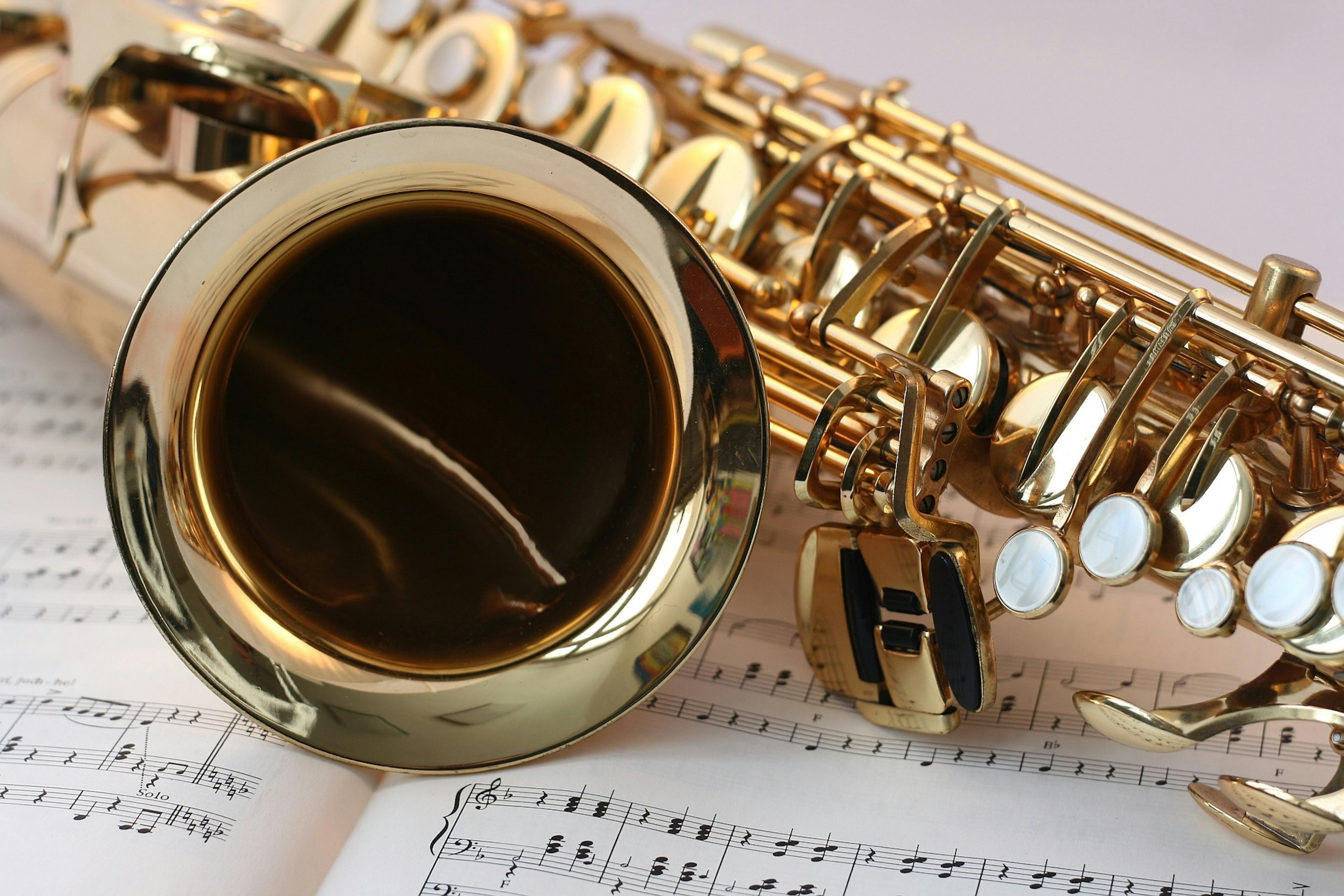 A detailed view of a saxophone resting on sheet music, highlighting its brass finish.