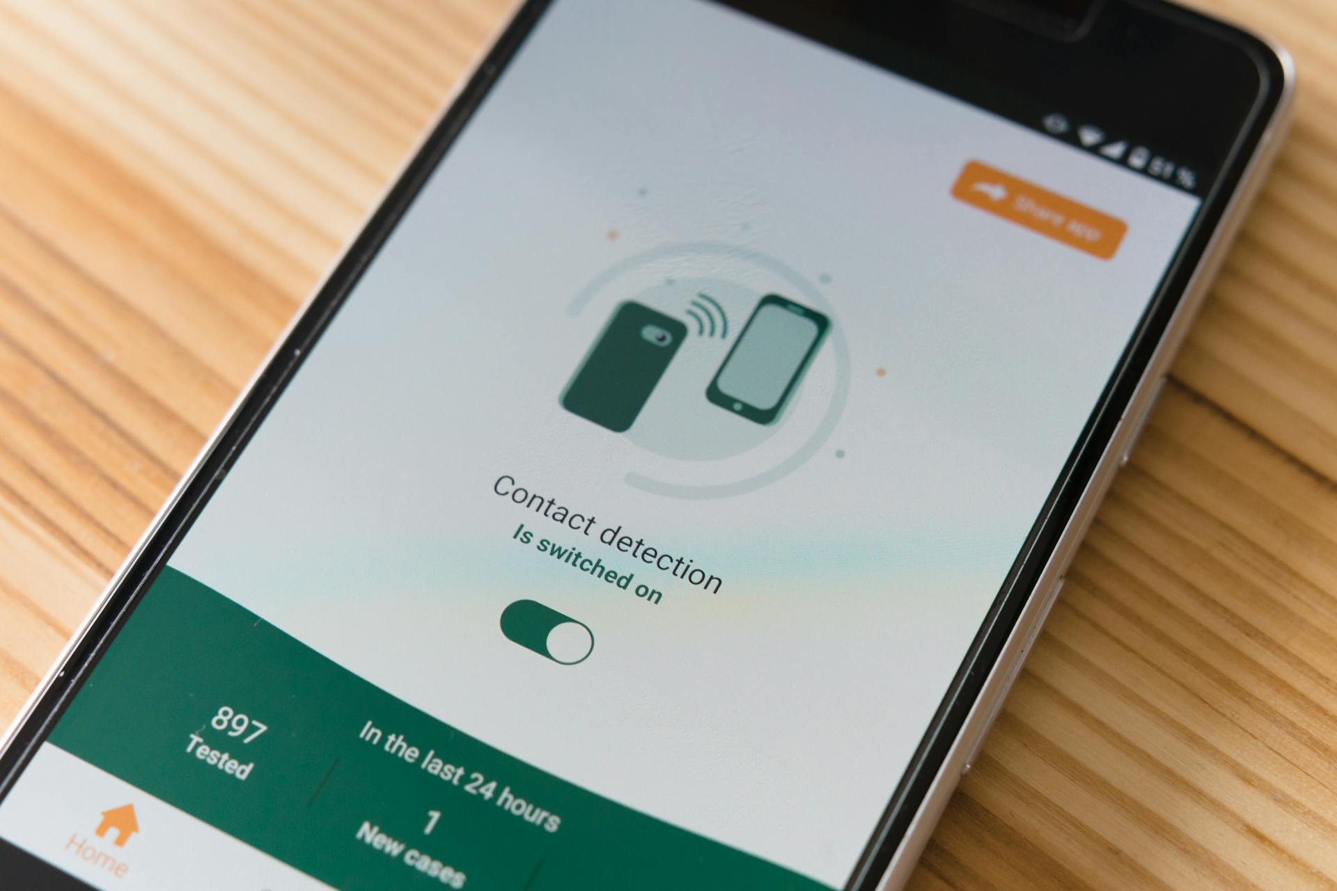 Close-up of smartphone displaying contact detection app on wooden surface.