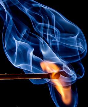 Dynamic macro shot capturing a matchstick ignited with vivid flames and swirling smoke.