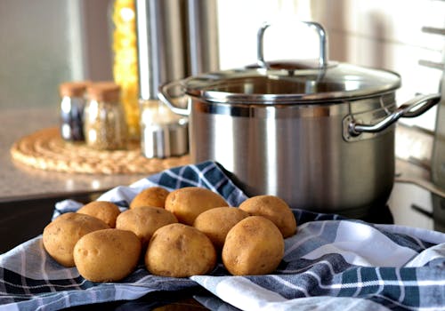 Patatas Al Lado De Una Olla De Acero Inoxidable