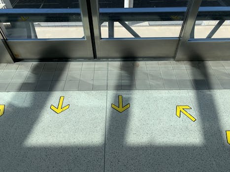 A contemporary airport hallway with yellow arrows guiding directions on the tiled floor.
