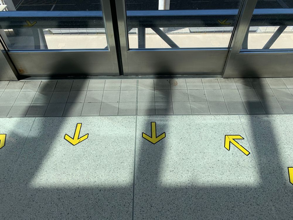 Yellow arrows on tiled floor in building · Free Stock Photo