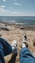 Person in Blue Jeans and White Sneakers on the Beach