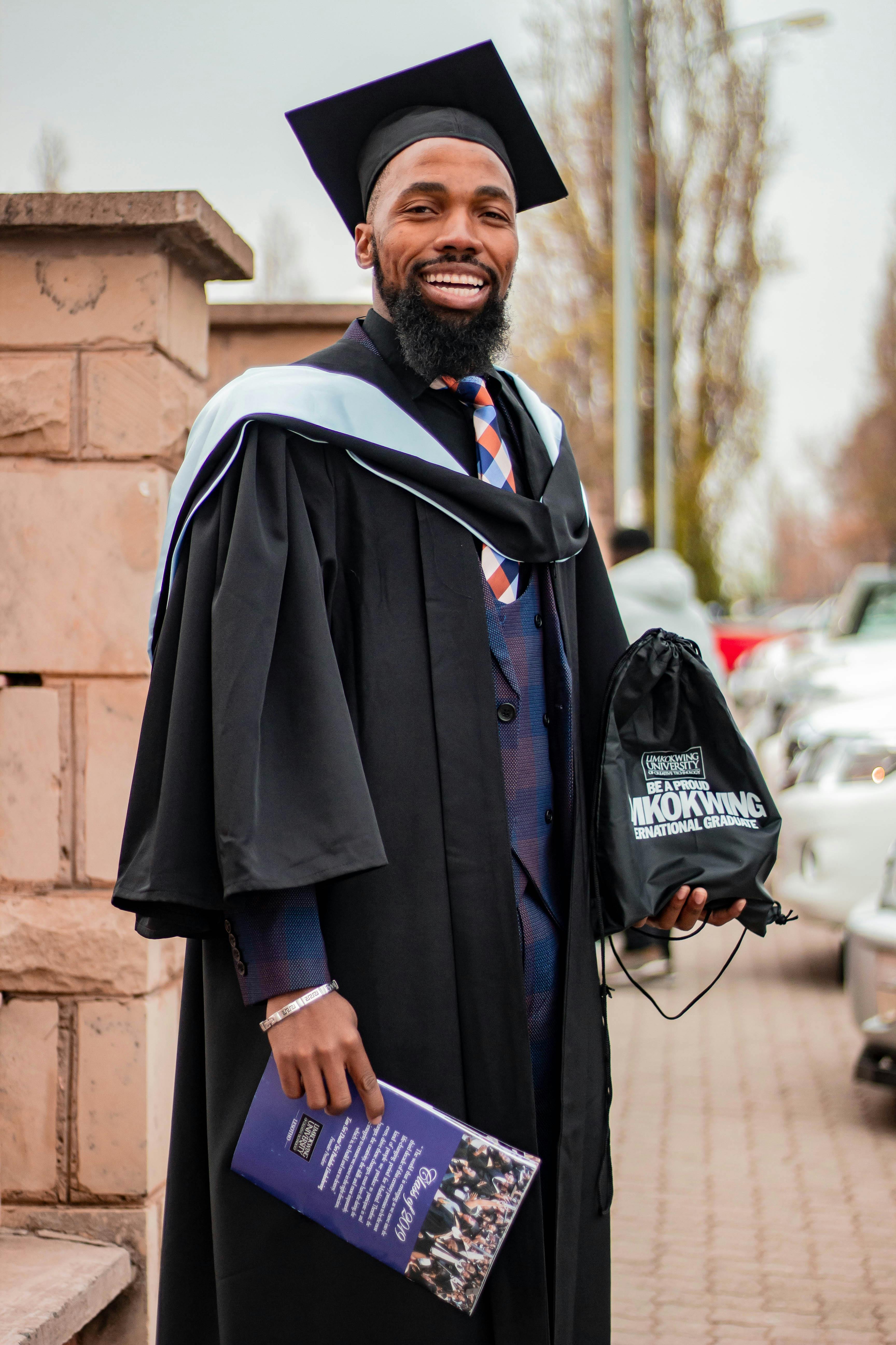 Happy black university graduate in academic outfit on street · Free Stock  Photo