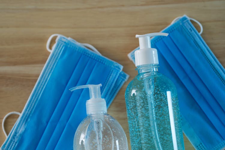 Liquid Soap And Gel Dispensers With Medical Masks On Table