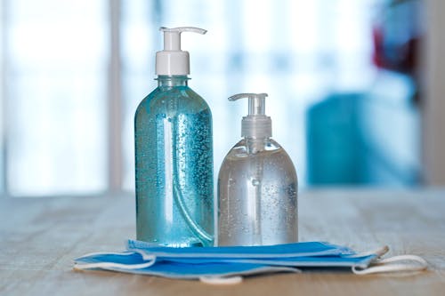 Free Antibacterial gels in plastic bottles and face masks at home Stock Photo