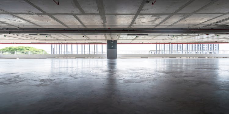 Spacious Covered Parking With Shiny Floor Behind Modern Buildings