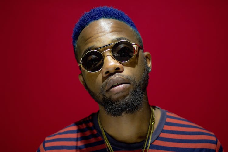 Stylish Black Hipster Man With Dyed Hair On Red Background