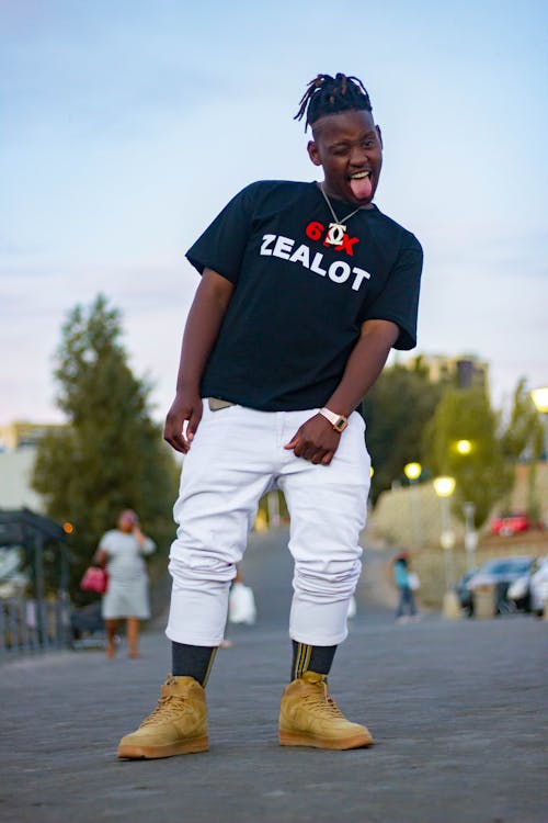 Stylish black man with tongue out standing on road