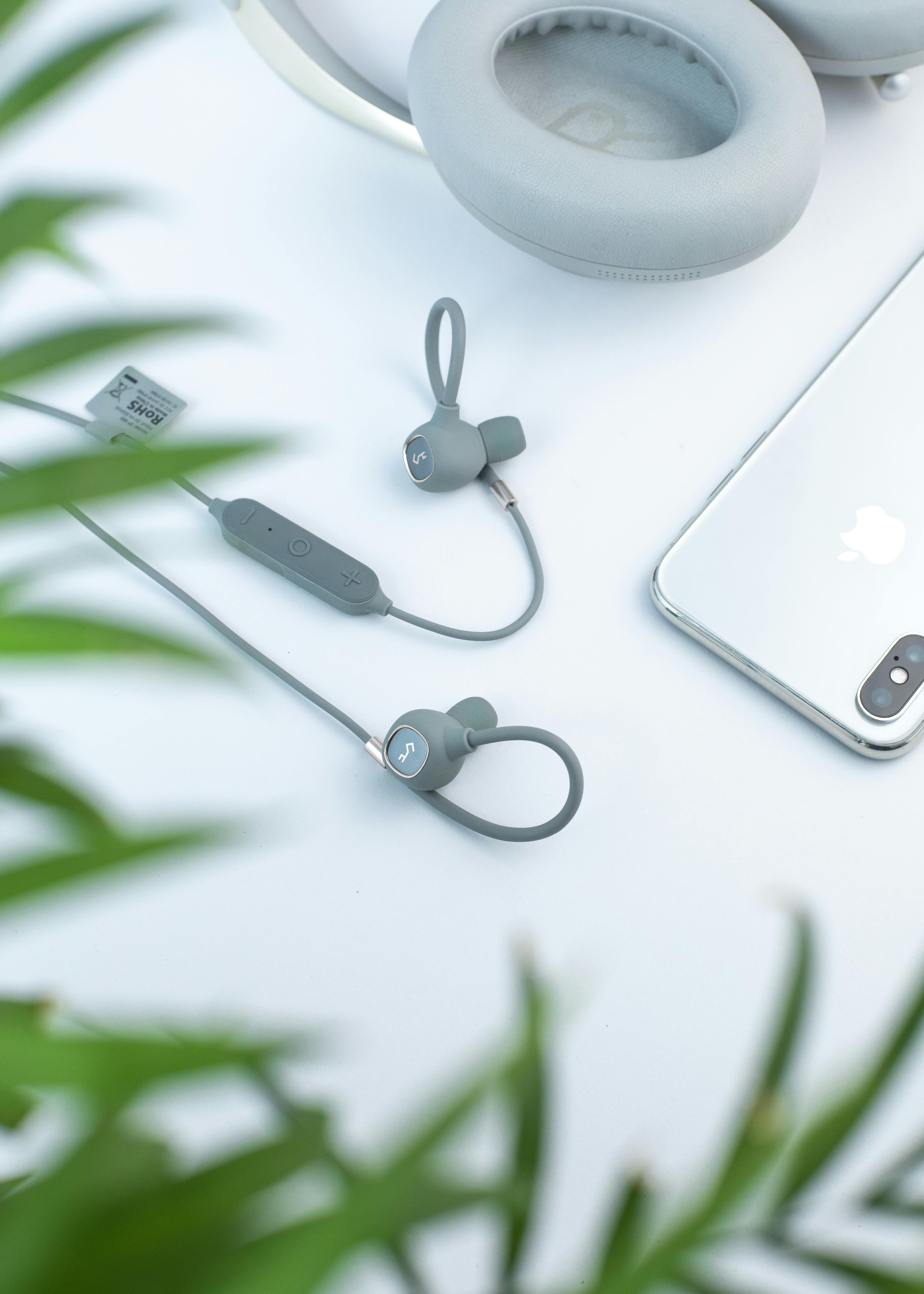 contemporary earphones and headphones on white table near smartphone