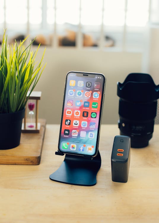 Free Smartphone on desk near power supply and camera lens Stock Photo