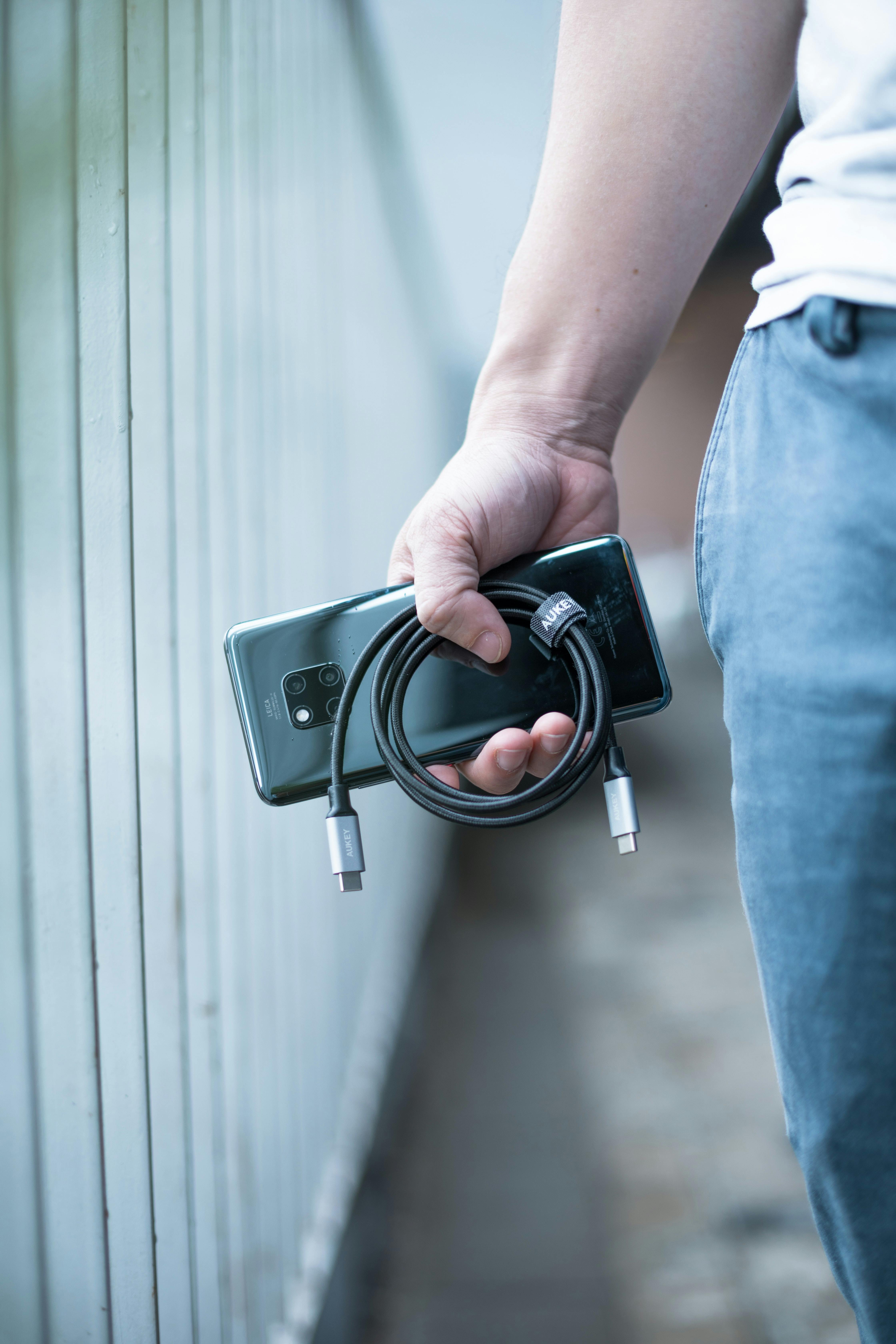 faceless person with modern smartphone and usb cable