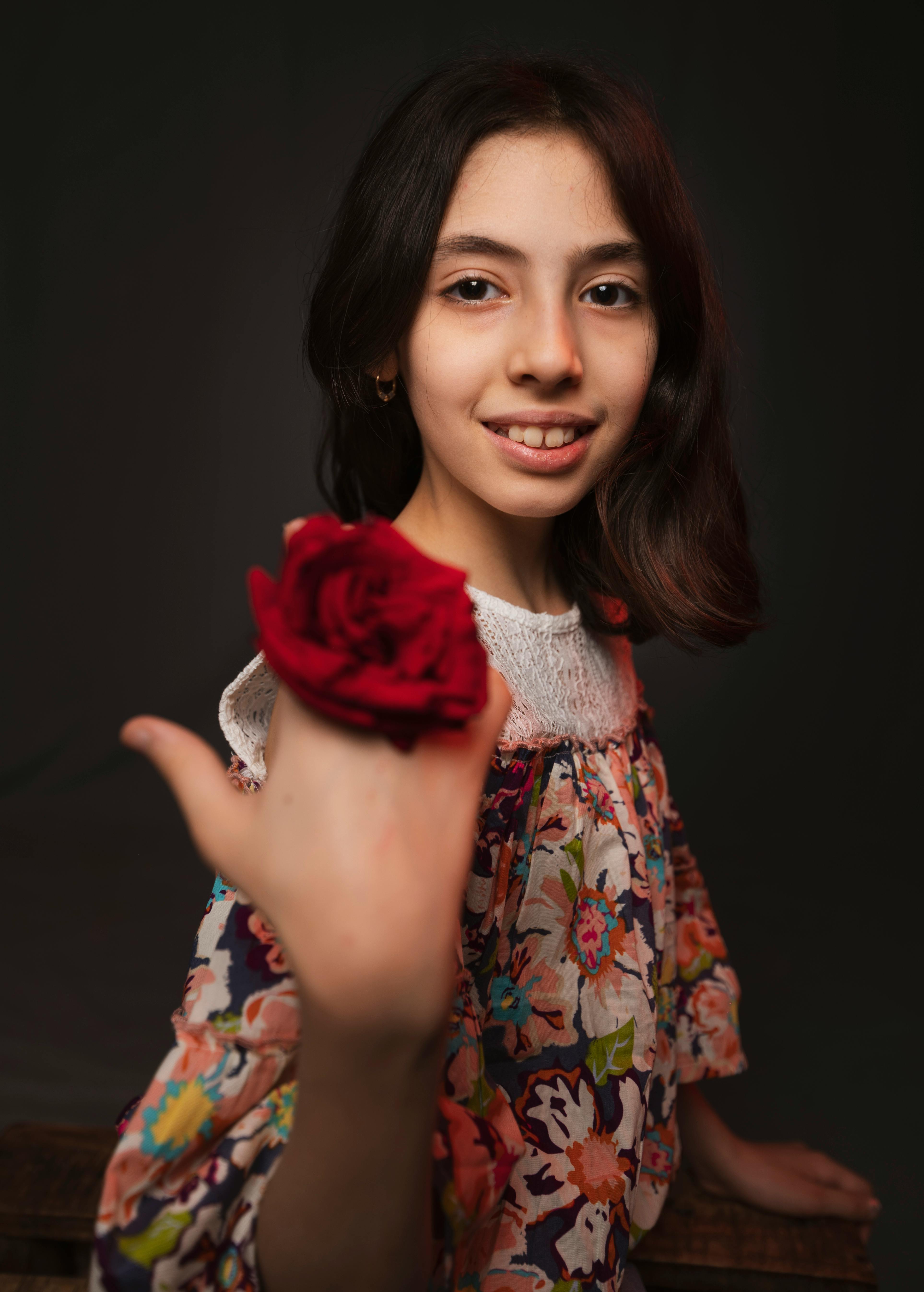 smiling ethnic adolescent with colorful red rose on black background