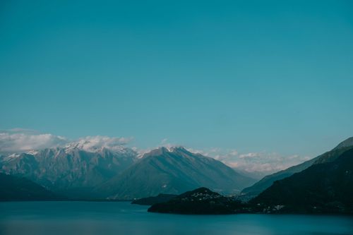 Free Picturesque view of rough snowy mounts near serene lake under blue cloudy sky in evening Stock Photo