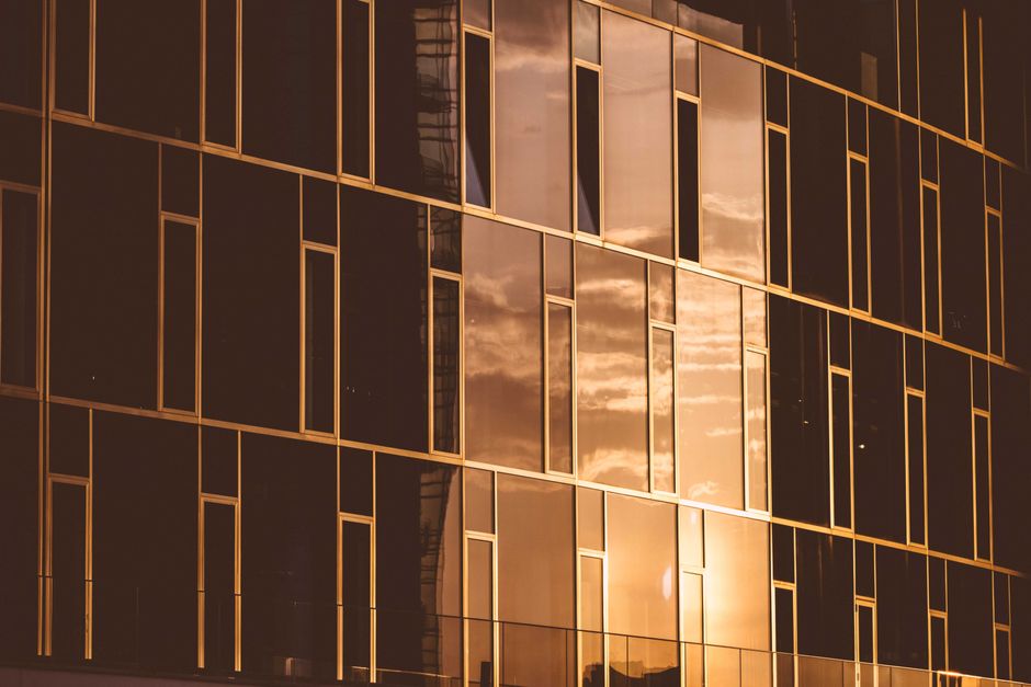 Contemporary multistage house exterior with shiny wall reflecting colorful cloudy sky at sunset in town