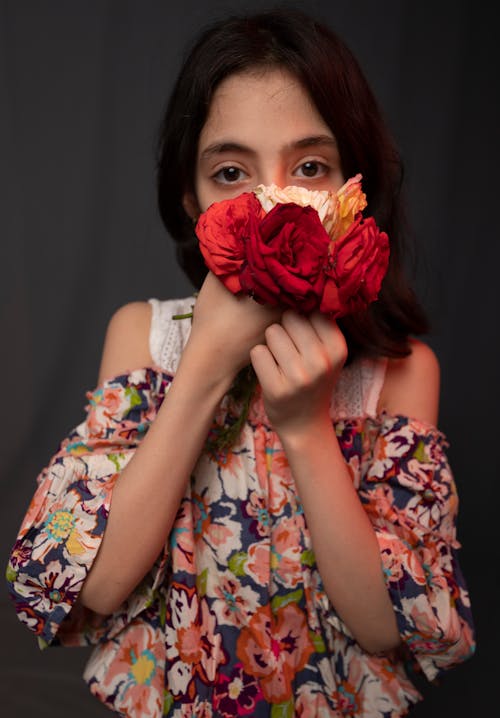 Young lady smelling fresh flowers and looking at camera